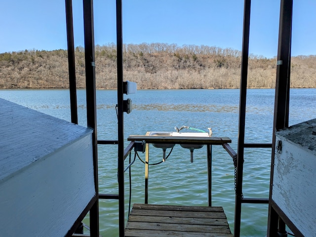 view of dock featuring a wooded view and a water view