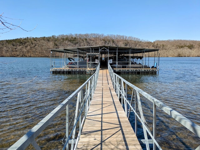 view of dock featuring a wooded view and a water view