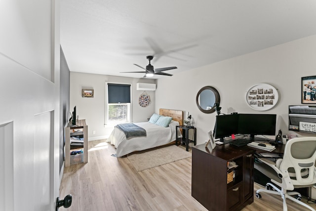 bedroom with light wood-type flooring, baseboards, an AC wall unit, and ceiling fan