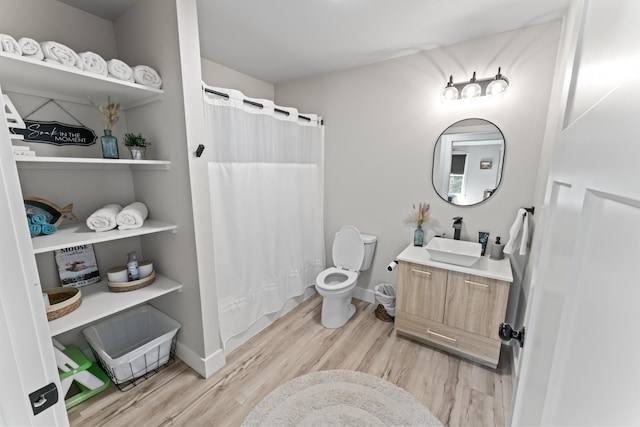 bathroom featuring toilet, curtained shower, wood finished floors, baseboards, and vanity