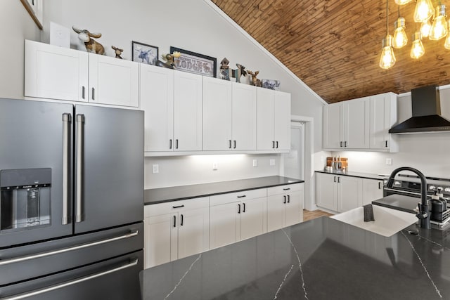 kitchen with stainless steel refrigerator with ice dispenser, dark countertops, wall chimney exhaust hood, white cabinets, and wood ceiling