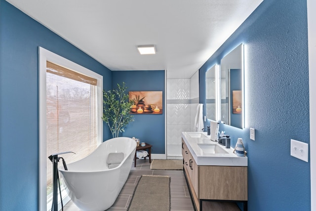 bathroom with double vanity, wood finished floors, a freestanding bath, and a sink