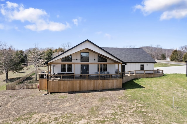 rear view of property featuring a deck, a yard, and fence