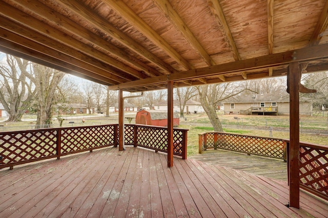 wooden deck featuring an outbuilding, a storage unit, and a yard