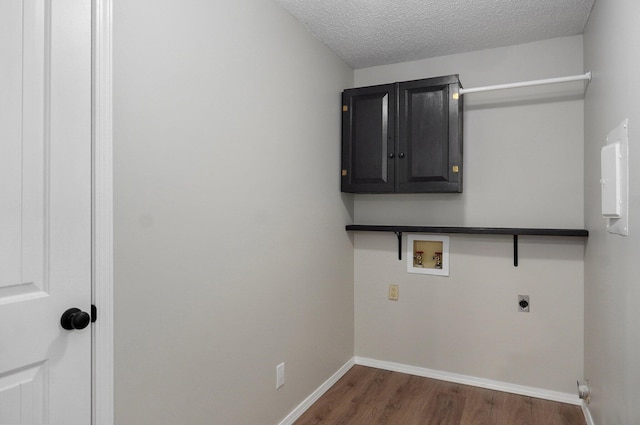 washroom with dark wood-type flooring, washer hookup, a textured ceiling, cabinet space, and hookup for an electric dryer