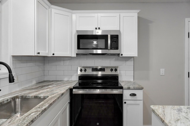 kitchen with white cabinets, tasteful backsplash, appliances with stainless steel finishes, and a sink