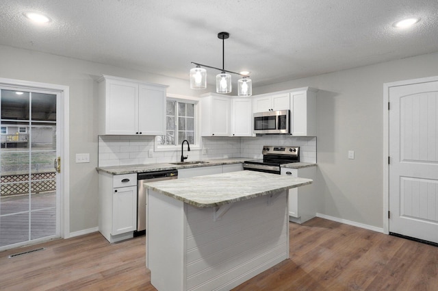 kitchen featuring a sink, stainless steel appliances, wood finished floors, and white cabinets