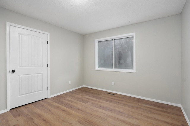 empty room featuring visible vents, baseboards, and light wood finished floors