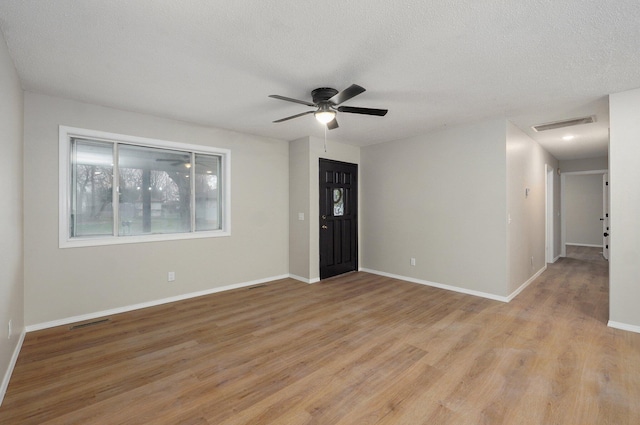 empty room with visible vents, a textured ceiling, a ceiling fan, and light wood-style floors