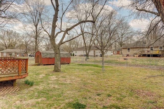 view of yard with an outbuilding, a storage unit, a deck, and fence