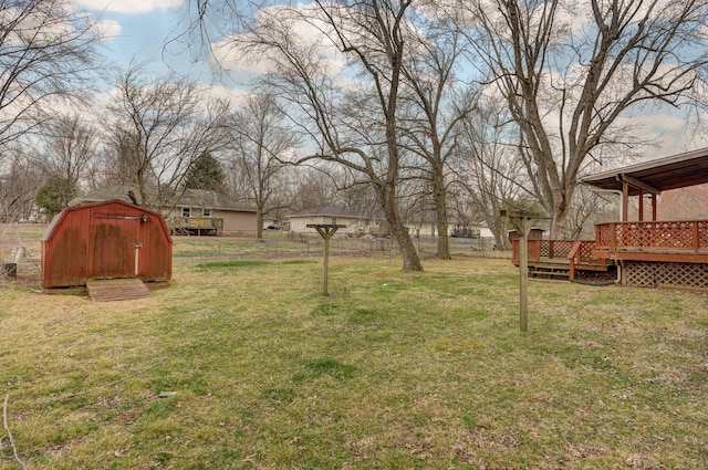 view of yard featuring an outdoor structure, a storage unit, fence, and a wooden deck