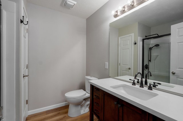 full bath featuring visible vents, walk in shower, toilet, wood finished floors, and vanity