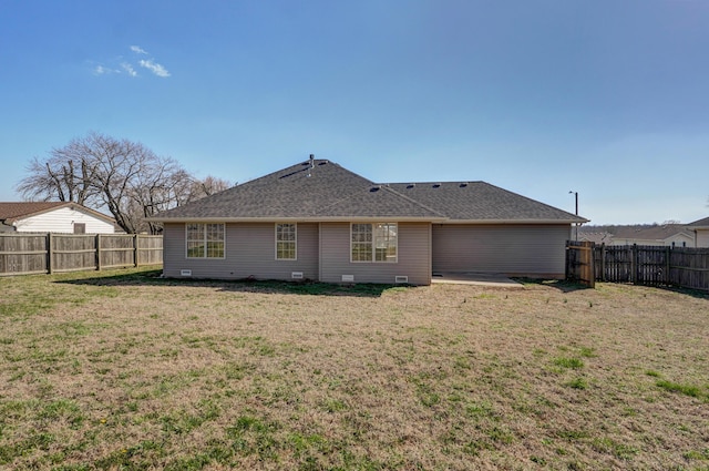 rear view of house featuring a yard, a fenced backyard, and a shingled roof