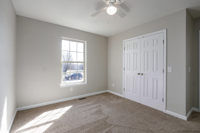 unfurnished bedroom with visible vents, a closet, carpet, baseboards, and ceiling fan