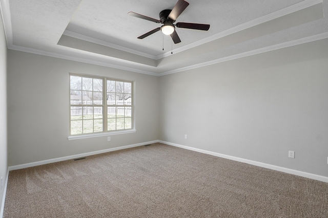 carpeted empty room with visible vents, baseboards, a raised ceiling, and ceiling fan