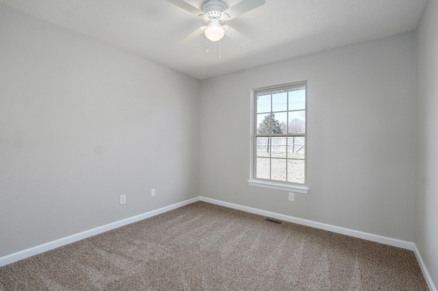 carpeted spare room with a ceiling fan, visible vents, and baseboards