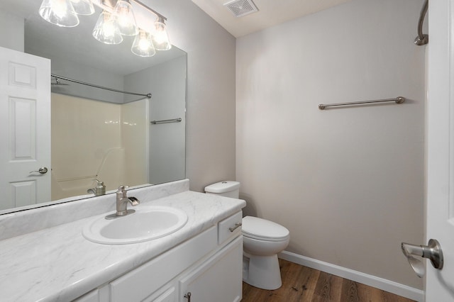 bathroom with vanity, wood finished floors, visible vents, baseboards, and toilet