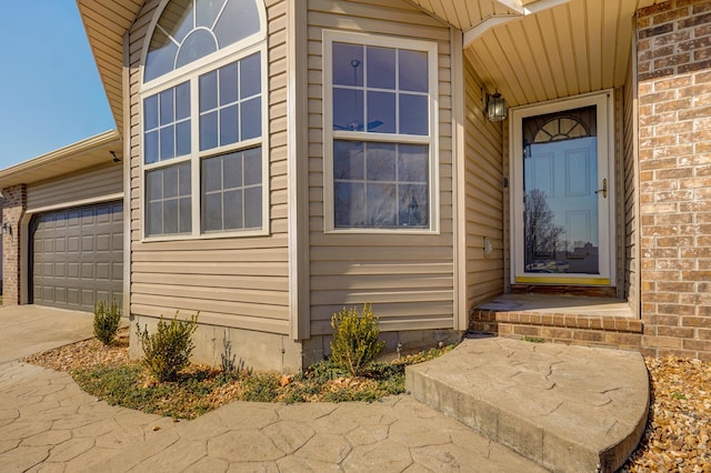 view of exterior entry with an attached garage and concrete driveway