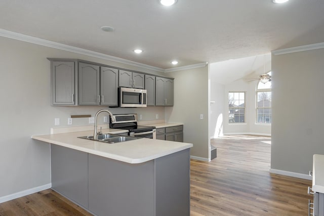 kitchen with gray cabinets, a sink, appliances with stainless steel finishes, a peninsula, and light countertops