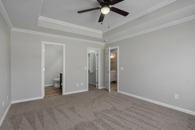 unfurnished bedroom featuring a tray ceiling, crown molding, baseboards, and carpet floors