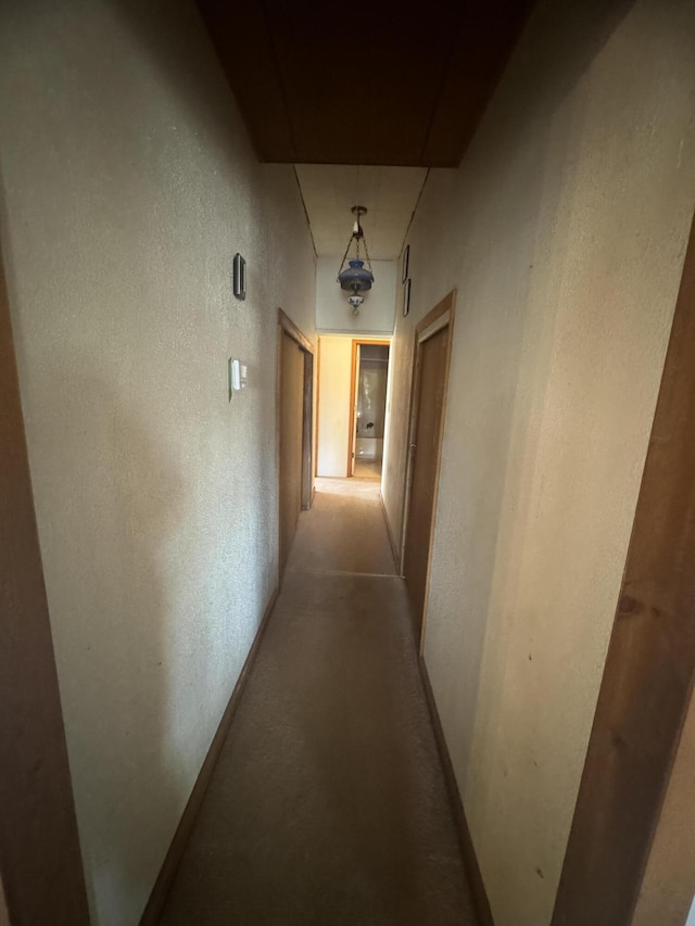 hallway featuring baseboards and a textured wall