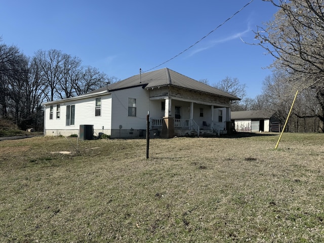 rear view of property featuring an outbuilding, a lawn, cooling unit, covered porch, and crawl space