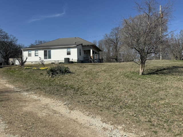 exterior space with crawl space, metal roof, a yard, and cooling unit