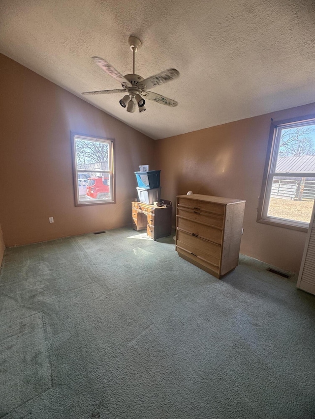 unfurnished bedroom featuring visible vents, a ceiling fan, a textured ceiling, carpet flooring, and lofted ceiling