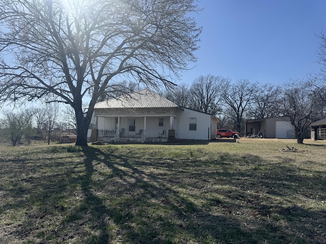 rear view of house with an outbuilding, covered porch, and a lawn