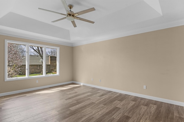 unfurnished room featuring baseboards, a raised ceiling, ceiling fan, and wood finished floors