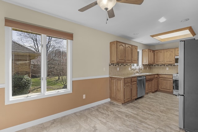 kitchen featuring tasteful backsplash, stainless steel appliances, brown cabinetry, light countertops, and ceiling fan