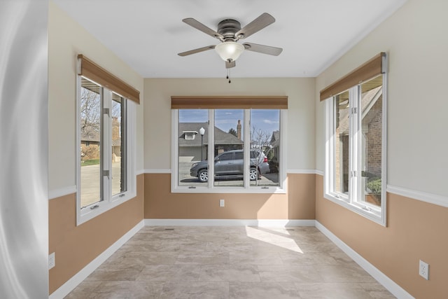 empty room featuring a wealth of natural light, baseboards, and ceiling fan