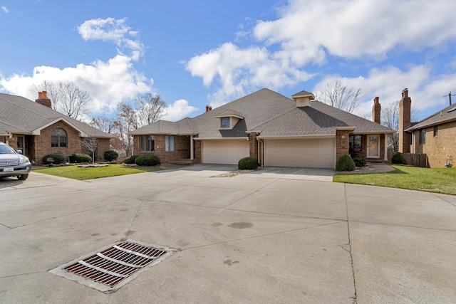 view of front of home with a front yard, brick siding, an attached garage, and driveway