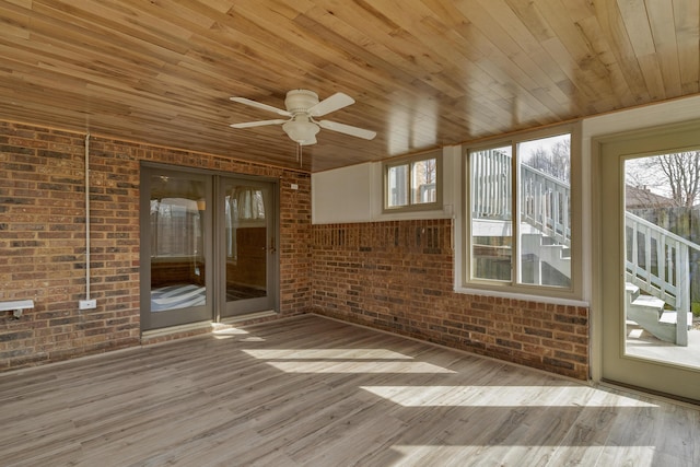 unfurnished sunroom featuring a healthy amount of sunlight, wooden ceiling, and ceiling fan