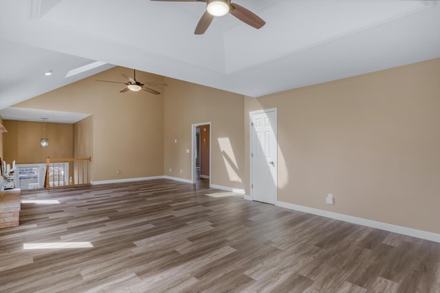 unfurnished living room with wood finished floors, a ceiling fan, baseboards, and high vaulted ceiling