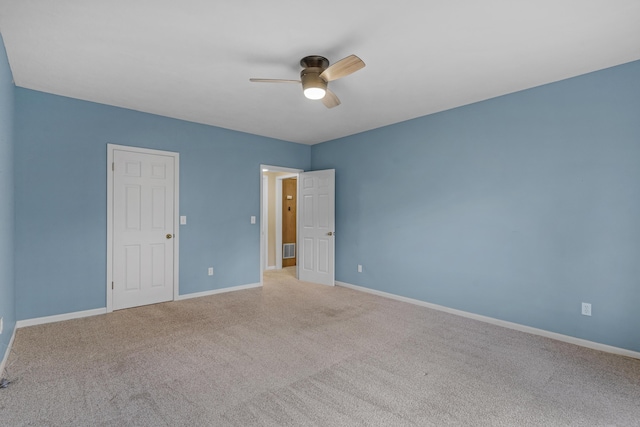 carpeted spare room featuring visible vents, baseboards, and a ceiling fan