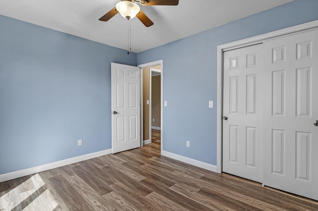 unfurnished bedroom with dark wood finished floors, a ceiling fan, baseboards, and a closet