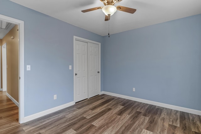 unfurnished bedroom with a ceiling fan, wood finished floors, a closet, and baseboards