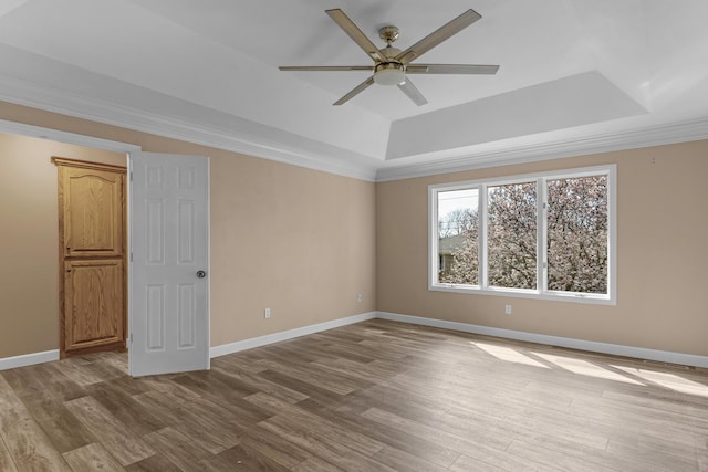 unfurnished room featuring baseboards, a raised ceiling, ceiling fan, and wood finished floors