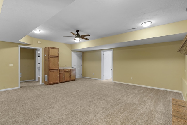 unfurnished living room with baseboards, light colored carpet, visible vents, and ceiling fan