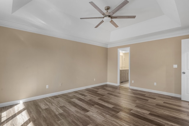 unfurnished room featuring a raised ceiling, ornamental molding, a ceiling fan, dark wood finished floors, and baseboards