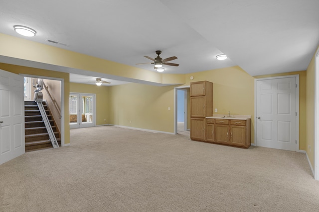 interior space featuring visible vents, baseboards, light carpet, a ceiling fan, and a sink