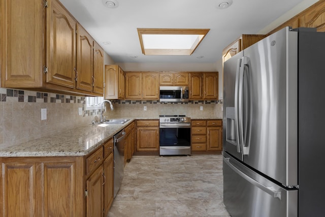 kitchen with a sink, stainless steel appliances, tasteful backsplash, and brown cabinetry