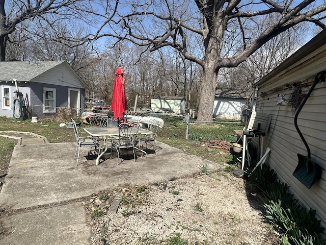 view of yard with a patio area, outdoor dining area, fence, and an outdoor structure