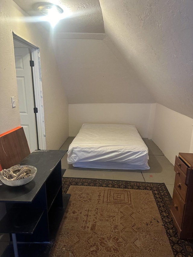 bedroom featuring vaulted ceiling and a textured ceiling