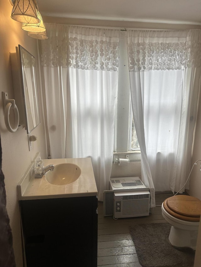 bathroom featuring a wall mounted air conditioner, toilet, vanity, and hardwood / wood-style flooring