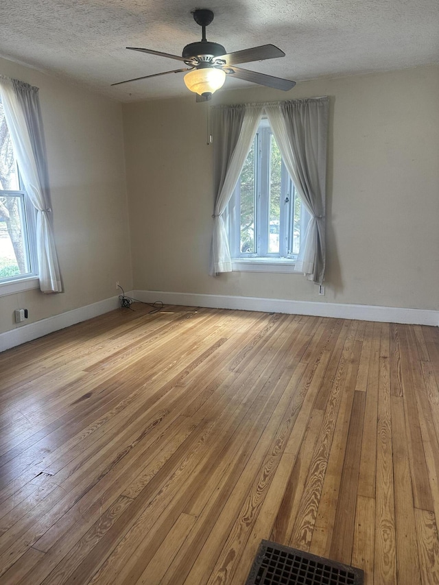 empty room with wood-type flooring, a healthy amount of sunlight, and ceiling fan