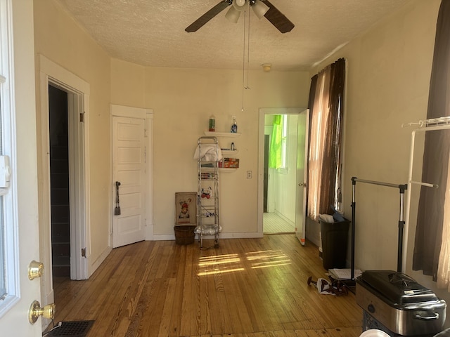 interior space with visible vents, baseboards, ceiling fan, a textured ceiling, and wood-type flooring