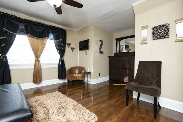 living area with a ceiling fan, wood finished floors, and baseboards