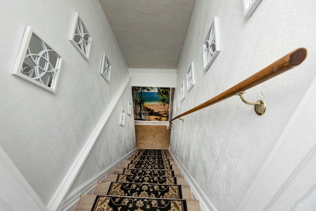 staircase with baseboards and a textured wall